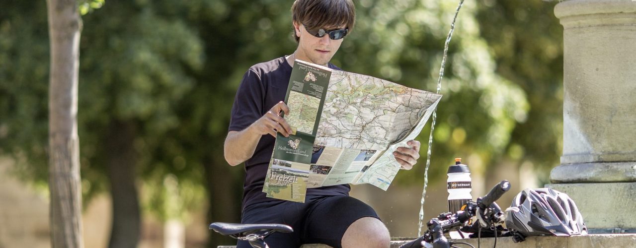 Ein Radfahrer auf dem Württemberger Weinradweg guckt sich eine analoge Karte an