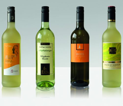 Verspielte Weißwein-Cuvées. Man sieht vier Flaschen Weißwein der Weinheimat Württemberg vor einem grauen Hintergrund.