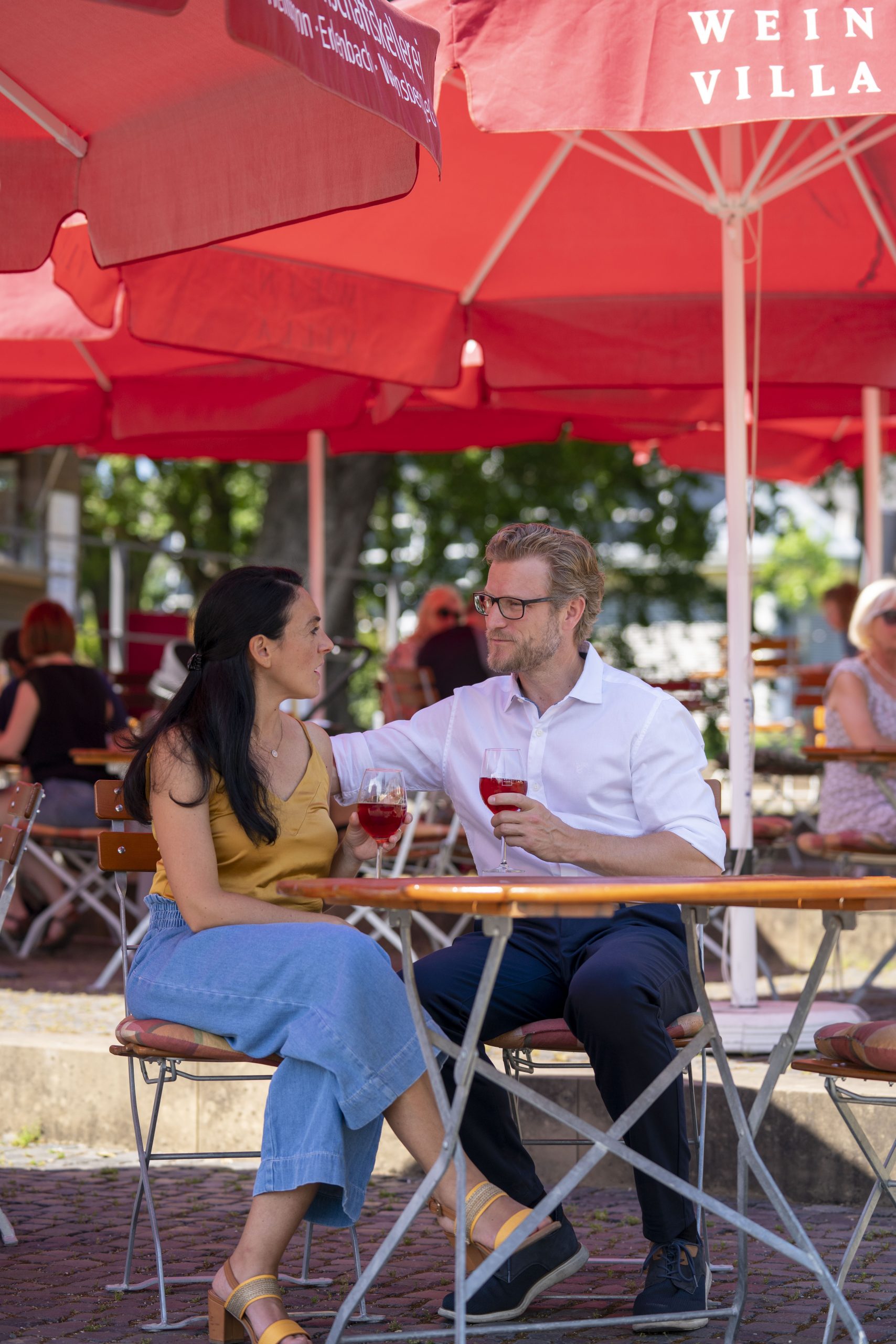 Ein Paar sitzt im Weinpavillon an der Neckarbühne unter einem Sonnenschirm und genießt ein Glas Wein