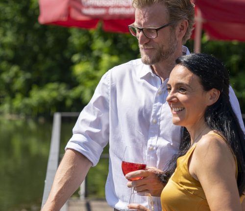 Ein Paar steht am Neckar und genießt ein Glas Wein