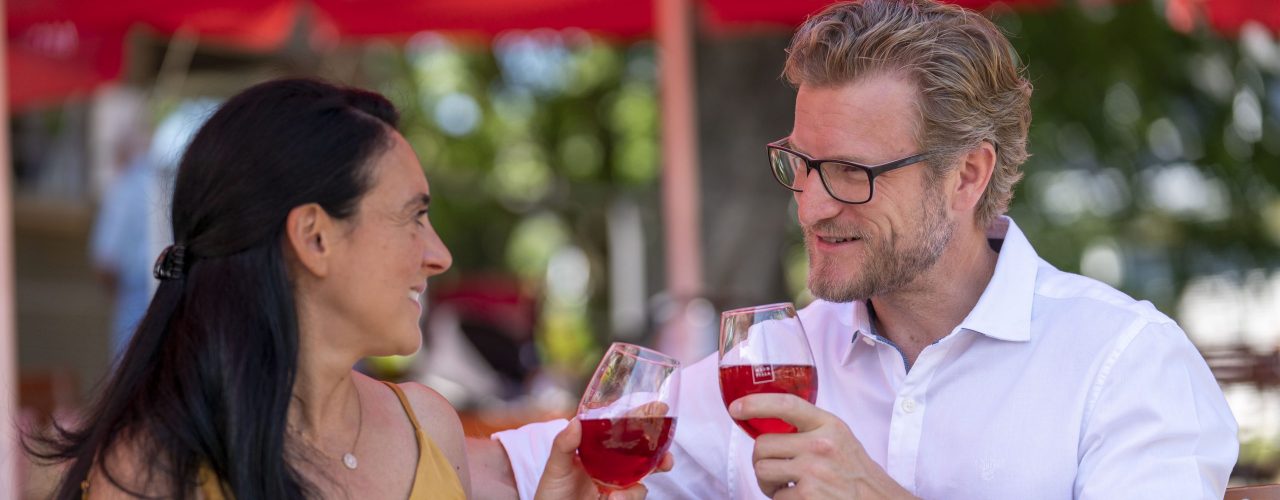 Ein Paar sitzt im Weinpavillon an der Neckarbühne und genießt ein Glas Wein