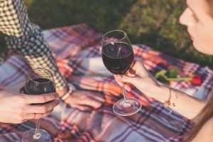 Paar stößt auf einer Picknick-Decke mit Rotwein an 
