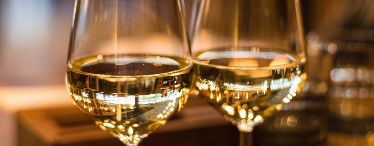 Live-Tastings im November. Man sieht zwei gefüllte Weingläser in warmem Licht.