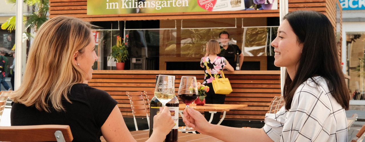 Weinausschank auf dem Kiliansplatz: Zwei Damen stoßen an vor dem Stand der Lauffeuer Weingärtner