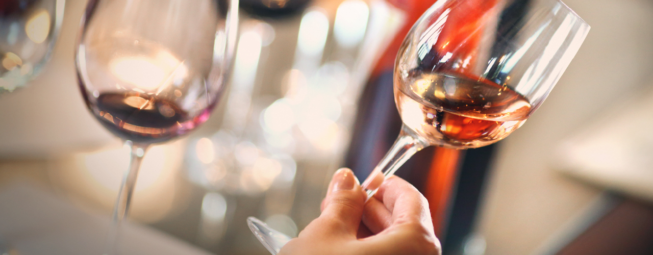 Weinverkostung, Frau hält prüfend ein Glas mit Wein in der Hand