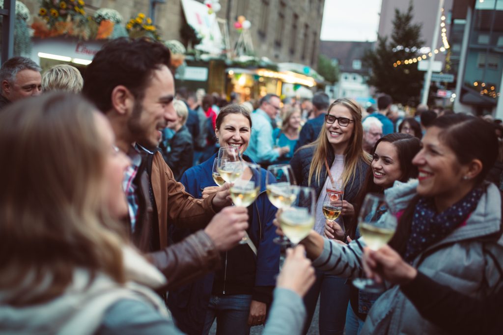 Mehrere junge Leute stoßen mit Weißwein auf dem Heilbronner Weindorf an.