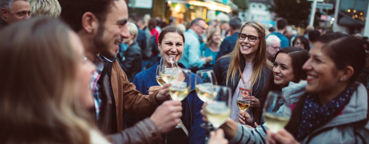 Mehrere junge Leute stoßen mit Weißwein auf dem Heilbronner Weindorf an.