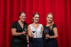 Die drei neuen Württemberger Weinhoheiten vor dem roten Vorhang: Weinprinzessin Lisa-Marie Blatt, Weinkönigin Carolin Häußer und Weinprinzessin Birthe Meseke