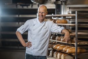 Andreas Schjrade lehnt in seiner Backstube lässig an einem Regal voller Brote