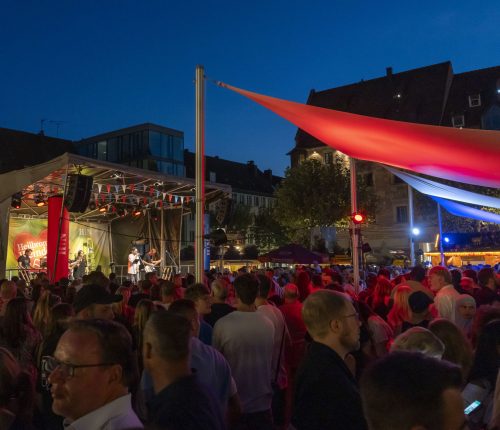 Blick auf das Heilbronner Weindorf am Abend, im Hintergrund sieht man Musiker auf der Bühne