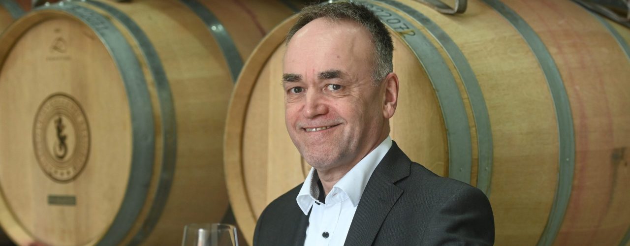 Der neue Vorstandsvorsitzende der Felsengartenkellerei, Eberhard Wolf, mit einem Glas Rotwein in der Hand, im Weinkeller der Felsengartenkellerei.