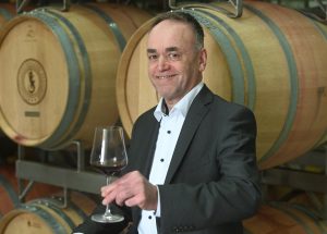 Der neue Vorstandsvorsitzende der Felsengartenkellerei, Eberhard Wolf, mit einem Glas Rotwein in der Hand, im Weinkeller der Felsengartenkellerei.