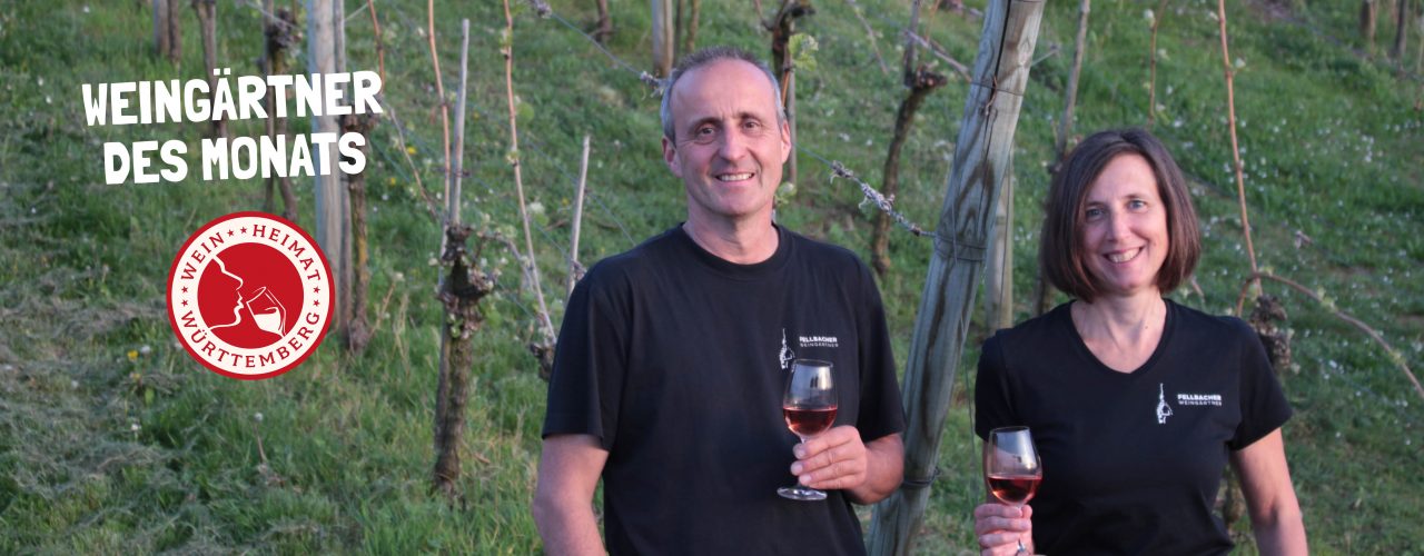 Matthias und Silvia Heid stehen mit jeweils einem Glas Weißwein im Weinberg, sie sind die Weingärtner des Monats April 2024.